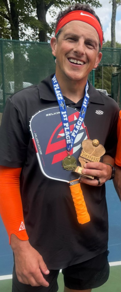 Matt Ryan holding a first-place medal and trophy after a pickleball tournament